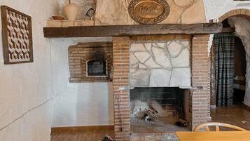 A stone fireplace with a brick surround, a decorative plate above it, and a woven basket on the floor.