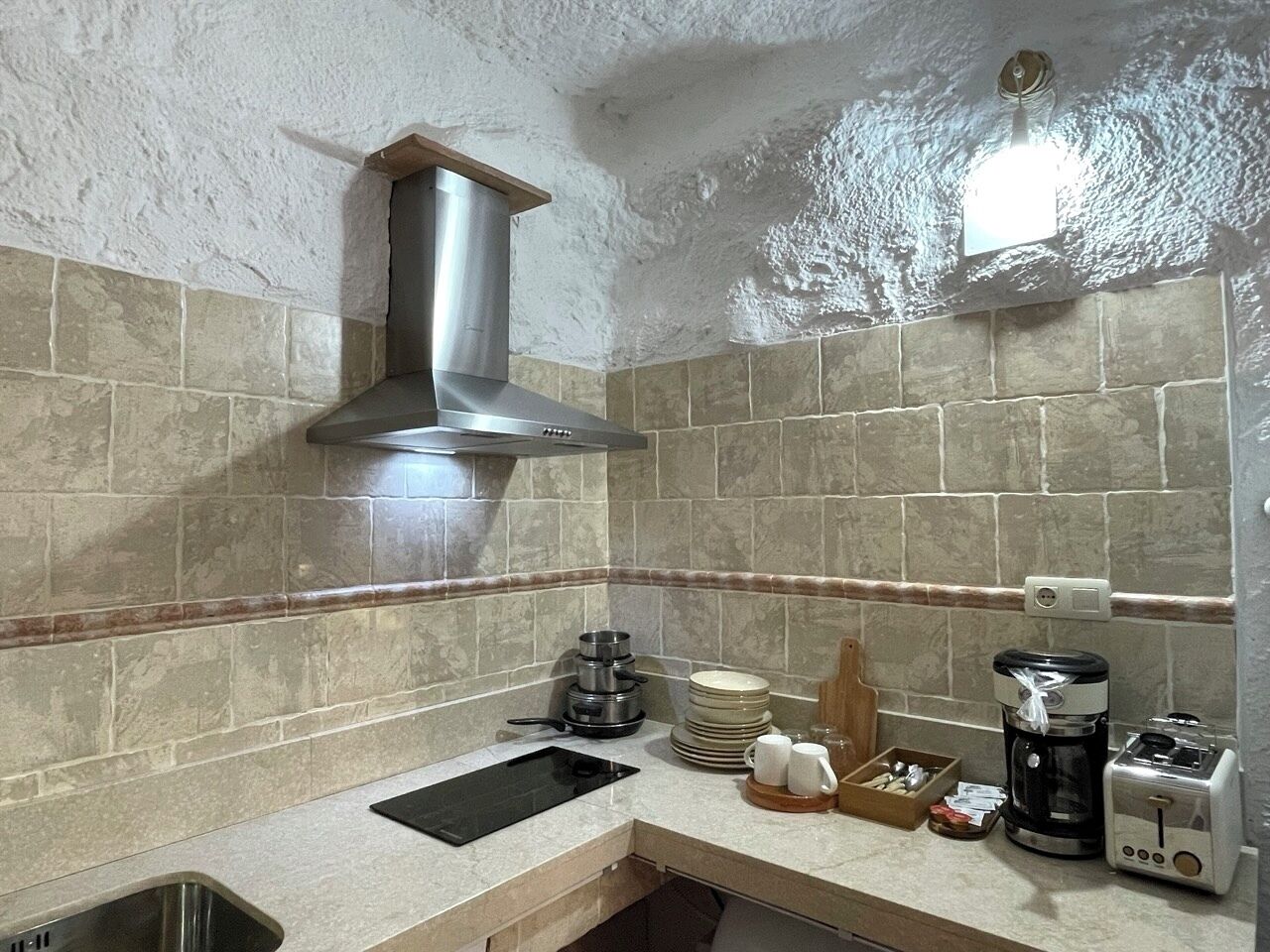 A kitchen with a stainless steel range hood, a sink, a coffee maker, and a toaster.