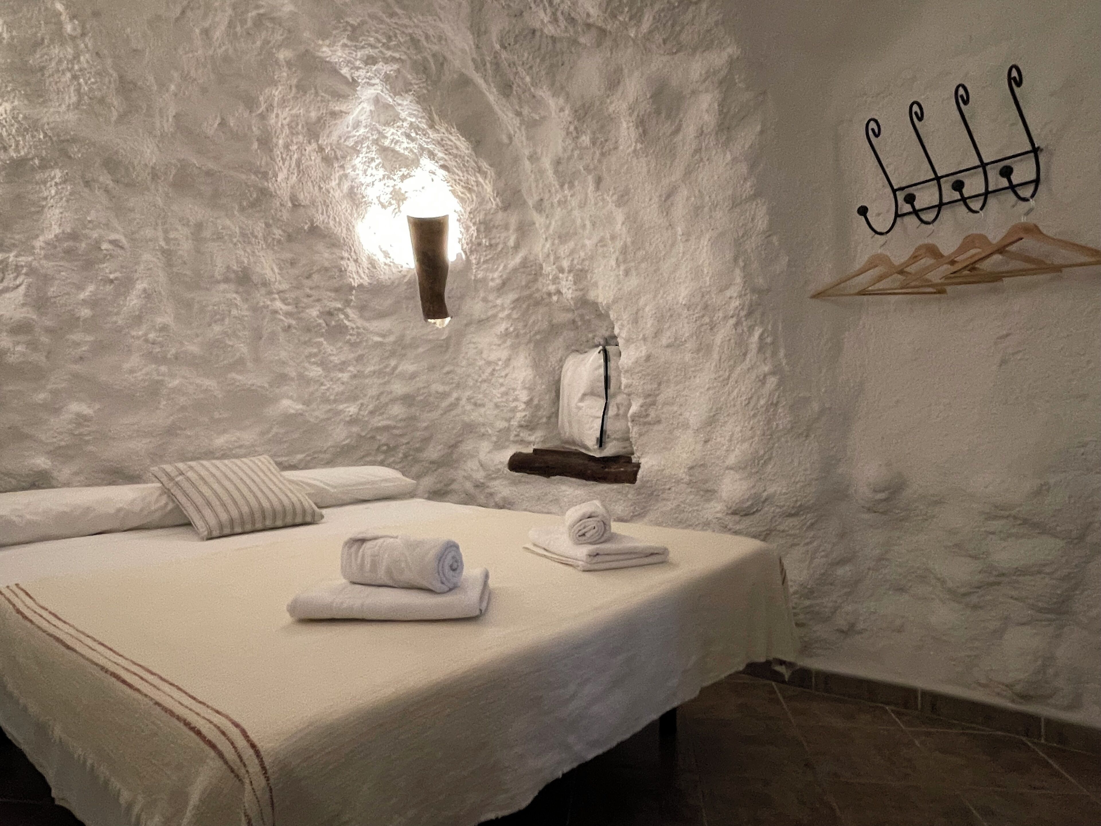 Une chambre confortable avec un lit, un porte-serviettes suspendu et une lampe fixée au mur.