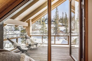 A wooden deck with a view of a snowy landscape and trees.
