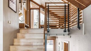 A wooden staircase with a metal handrail, leading to a room with a view of the outdoors. - Åre's best family home (Åre)
