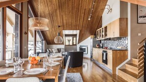 A modern kitchen with wooden cabinets, a dining area with a wooden table set for six, and a staircase leading to an upper level. - Åre's best family home (Åre)