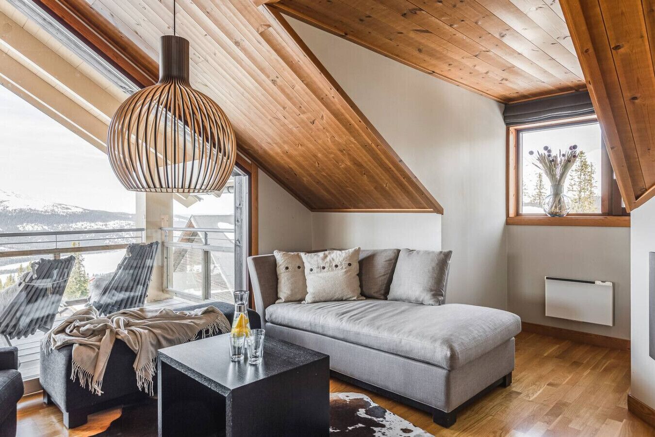 A cozy loft bedroom with a sloped ceiling, a sofa, a coffee table, and a view of the outdoors.