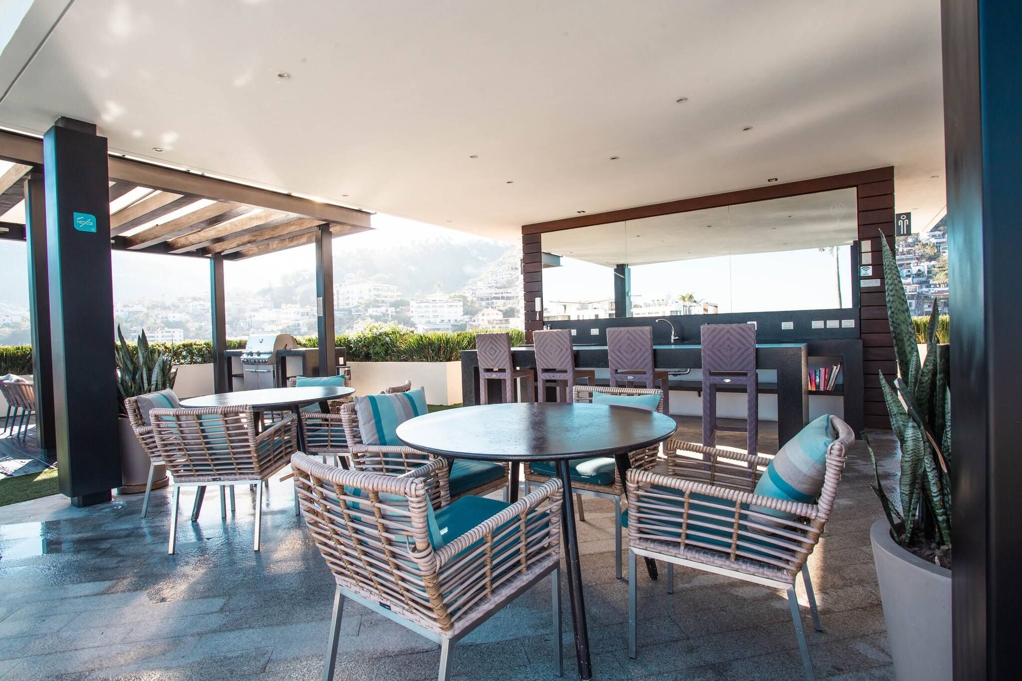 An outdoor patio with wicker furniture, a round table, and a grill.