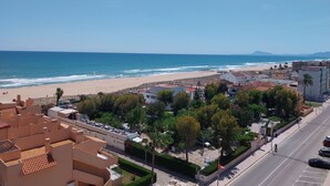 A coastal residential area with a beach, buildings with terracotta roofs, and a clear blue sky. - PARQUEMAR I  6º ATICO SOLO FAMILIAS! (Xeraco Playa)