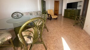 A dining area with a glass table and chairs, a sofa, a television, and a cabinet. - PARQUEMAR I  6º ATICO SOLO FAMILIAS! (Xeraco Playa)