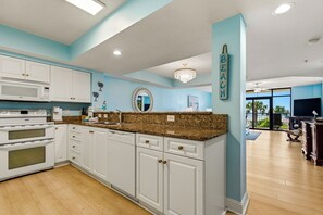 A kitchen with white cabinets, a granite countertop, and a microwave.