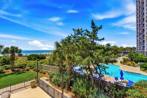 A resort with a swimming pool, palm trees, and a view of the ocean. - 🌴🌞Lazy River + Indoor/Outdoor Pools | Oceanfront | South Wind 208 (Myrtle Beach)