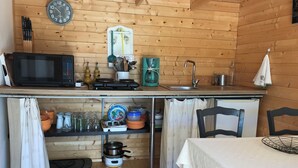 A compact kitchen with a microwave, stove, sink, and various utensils.