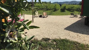 A gravel patio with outdoor seating, a table, and a view of a mountainous landscape.