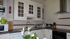 A kitchen with white cabinets, a Bosch dishwasher, a microwave, a sink, and a stove.