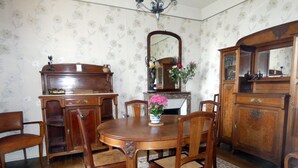 A dining room with a wooden table, chairs, a floral-patterned rug, and a floral wallpaper.