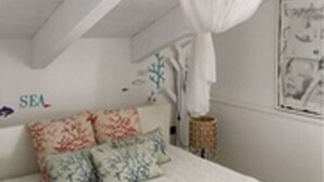 Ein Schlafzimmer mit Bett, Baldachin und einer Wand mit dem Schriftzug 'SEA'.