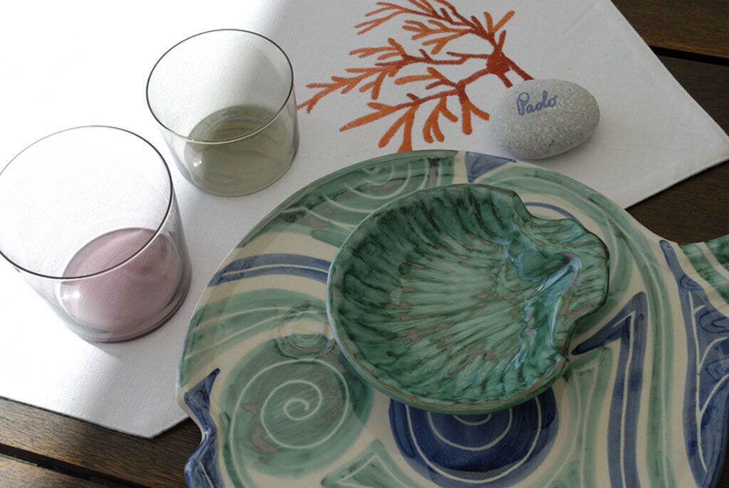Une table avec un verre, un bol, une assiette et une pierre sur laquelle est inscrit le mot « Pados ».