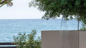 Ein Betongebäude mit Tür, einem kleinen Baum und Blick auf das Meer.