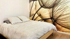 A bedroom with a bed, pillows, and a wall mural.