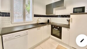 A modern kitchen with a dishwasher, oven, and a window with a view of greenery.