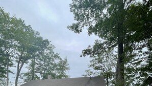 A single-story house with a front porch, a small front yard, and a view of a body of water. - Waterfront on Sebago Lake (STANDISH)