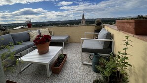 En tagterrasse med sofa, lille bord og plantekasser.