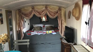 A bedroom with a bed, a television, and a window with curtains. - Roulotte 2 Personnes (Saint-Rémy-de-Provence)