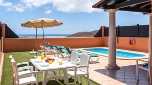 Eine Dachterrasse mit Pool, Sitzgelegenheiten im Freien und Blick auf den Ozean.