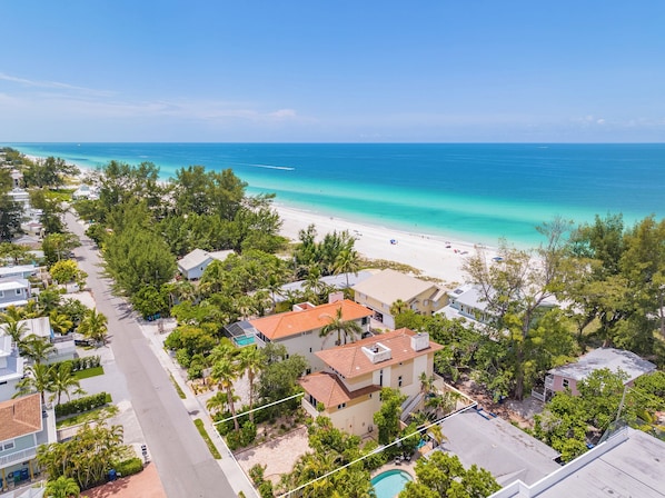 Zona residencial costera con playa, casas y piscina.