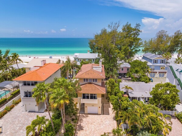 A coastal residential area with houses, a beach, and clear skies.