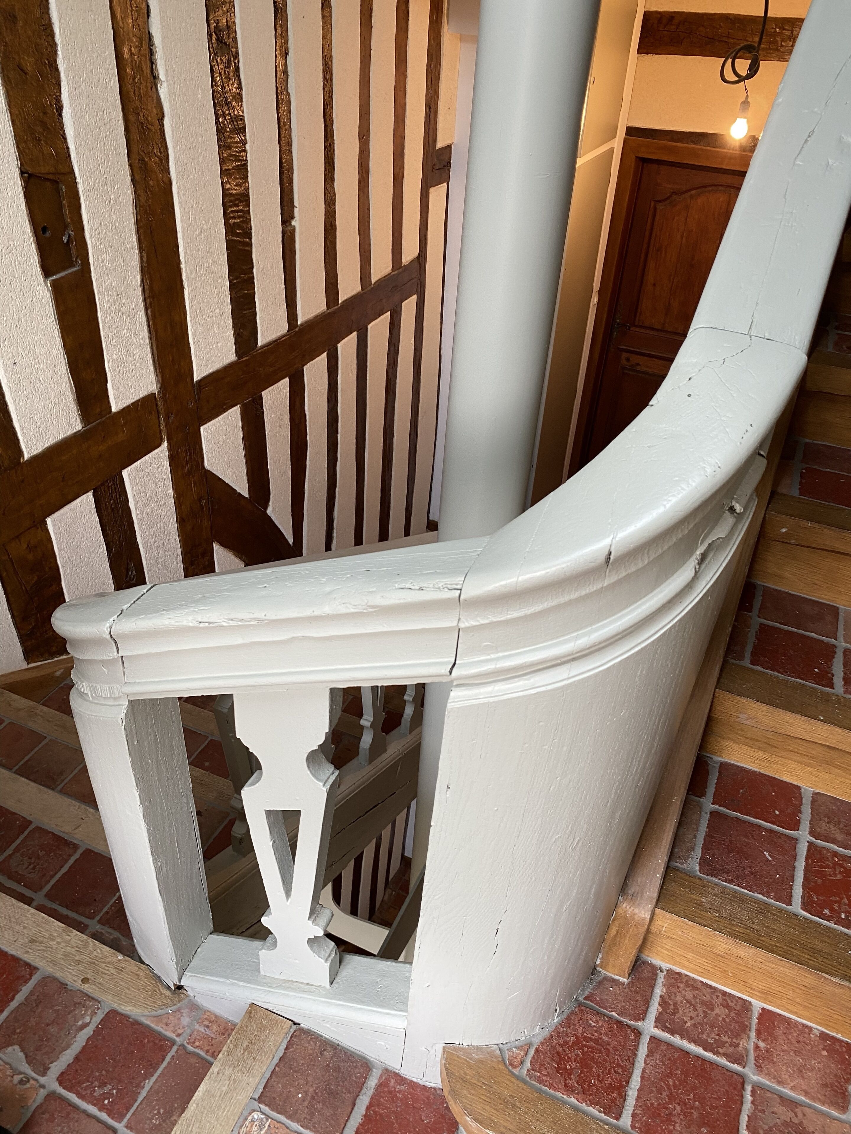 A white, curved staircase with a wooden railing.