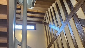 A wooden staircase with a metal handrail and a view of the upper floor.