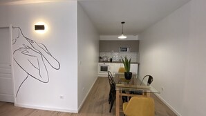 A modern kitchen with white cabinets, a microwave, and a potted plant. - Appartement REZ DE Chaussee (Amiens)