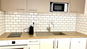 A kitchen with white cabinets, a microwave, a sink, and a stove. - Appartement REZ DE Chaussee (Amiens)