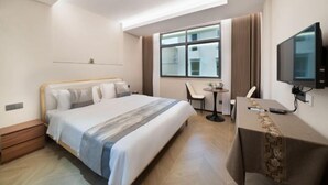 Une chambre d’hôtel avec un lit, un bureau, une chaise, une télévision et une fenêtre.