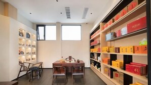 Une pièce moderne avec une table et des chaises en bois, une bibliothèque avec des boîtes colorées et une grande fenêtre laissant entrer la lumière naturelle.