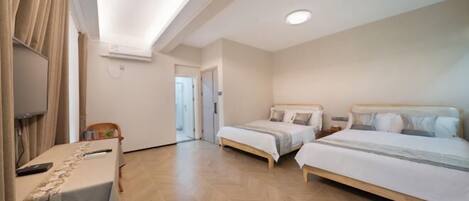 A hotel room with two beds, a desk, a TV, and a ceiling fan.