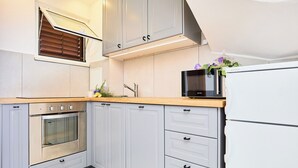 A modern kitchen with grey cabinets, a stainless steel oven, a microwave, and a refrigerator. - Hedera Estate, Hedera A16 (Dubrovnik)