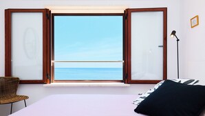 A bedroom with a bed, a chair, a nightstand, a lamp, and a window with a view of the sea. - Hedera Estate, Hedera A16 (Dubrovnik)