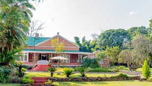 A two-story house with a brick exterior, a green roof, and a front porch.
