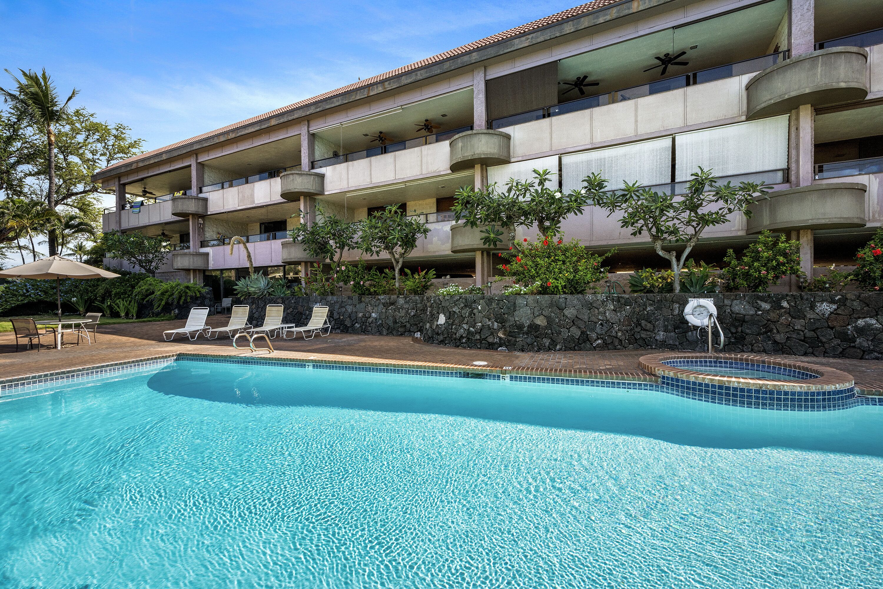 A hotel with a swimming pool, multiple balconies, and outdoor seating.