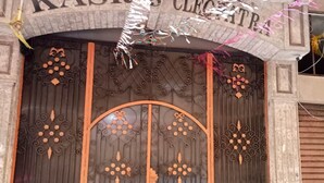 Una gran y ornamentada puerta de metal con intrincados diseños florales y la inscripción 