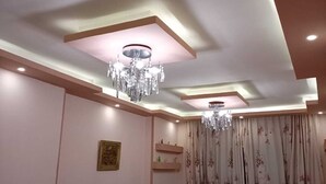Una sala de estar con un sofá color turquesa, dos candelabros y un ventilador.