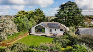 A modern house with a sloped roof, solar panels, and a large glass window. - The Garden House (Wadebridge)