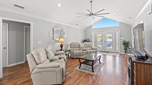 Un salon spacieux doté d’un haut plafond, d’un ventilateur de plafond et d’une grande fenêtre laissant entrer la lumière naturelle.