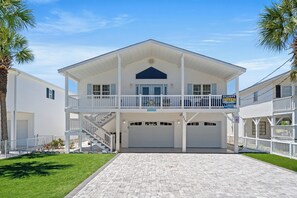 A two-story house with a covered front porch, a garage, and a staircase leading to the upper level. - Almost Retired - 3 Bed Cherry Grove Channel Home (North Myrtle Beach)