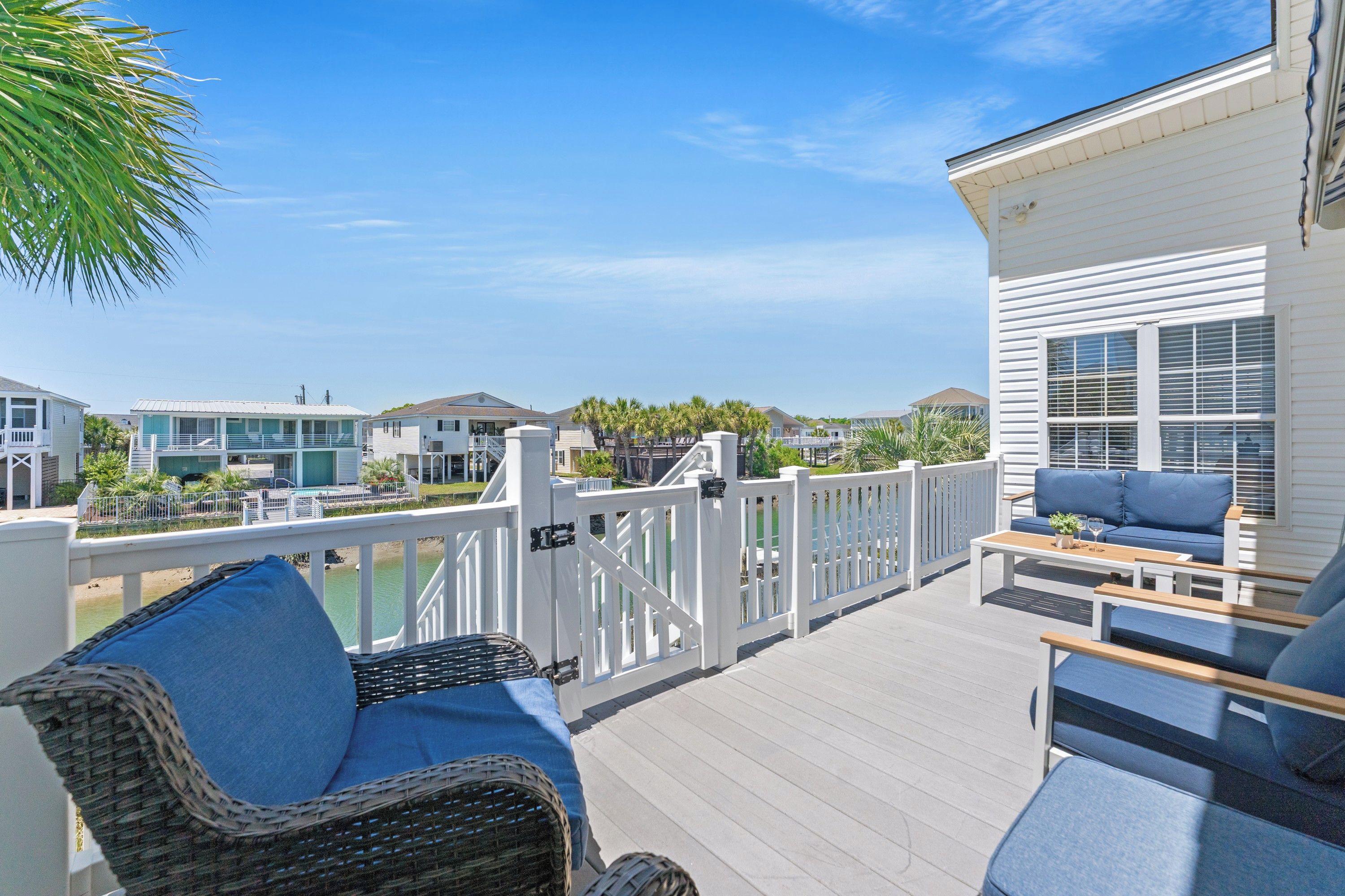 A deck with outdoor furniture, a view of neighboring houses, and a clear sky.