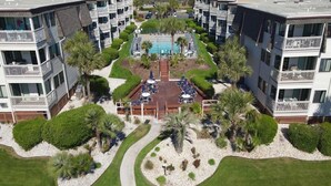 A multi-story hotel with balconies, a swimming pool, and a landscaped courtyard.