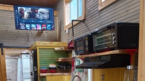Une cuisine de taille réduite, dotée de meubles en bois, d’un four à micro-ondes et d’un évier.