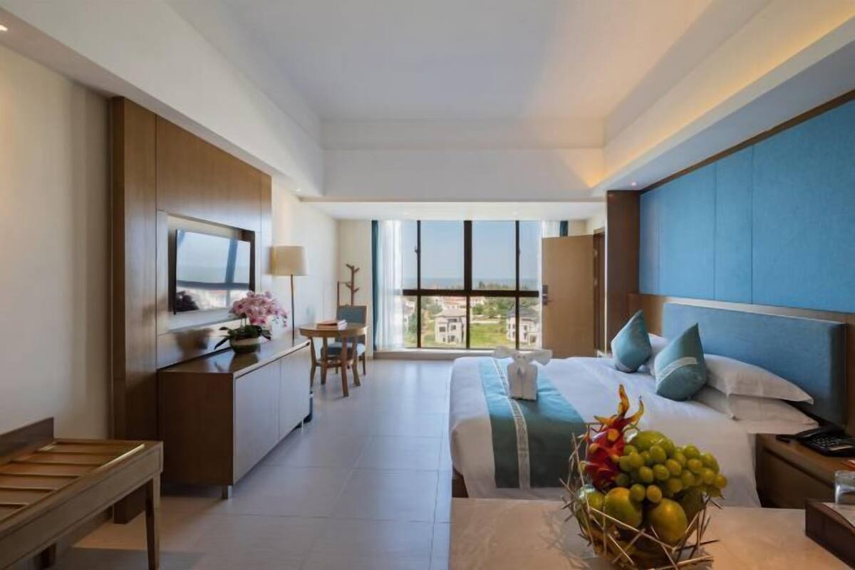 Een moderne hotelkamer met een groot bed, een bureau, een televisie en uitzicht op de stad.