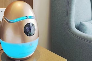 A modern, metallic air purifier with a digital display on a wooden surface.