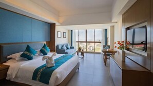 Une chambre d’hôtel avec un grand lit, un canapé, une télévision et un balcon avec vue.