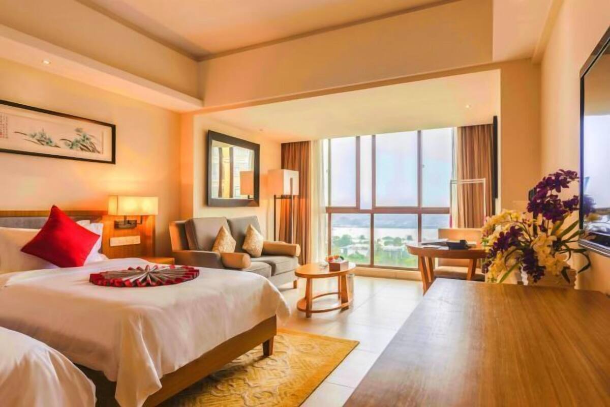 Een hotelkamer met een groot bed, een bank, een eettafel en uitzicht op het omliggende landschap.